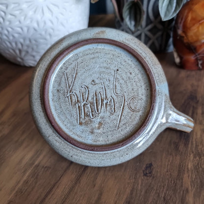 Krums speckled stoneware candle holder with side loop handle and earthy neutral glaze.