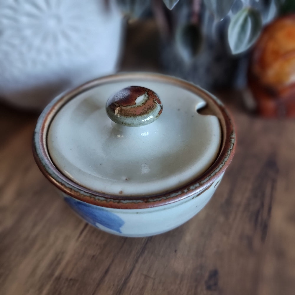 Lidded handmade pottery bowl with brown rim and blue brushstroke design