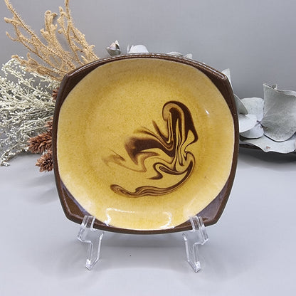 Retro mustard and brown swirl ceramic dish with square edges.