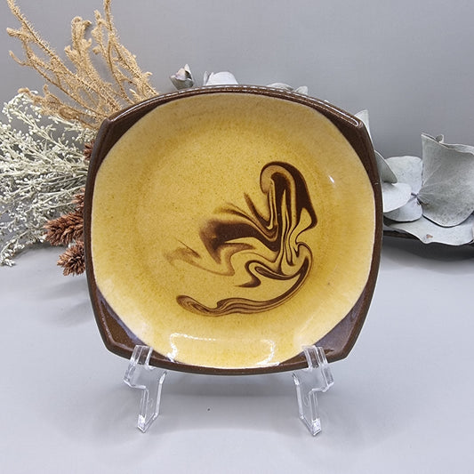 Retro mustard and brown swirl ceramic dish with square edges.