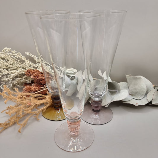 Set of three champagne flutes with pink, amber, and plum coloured bases