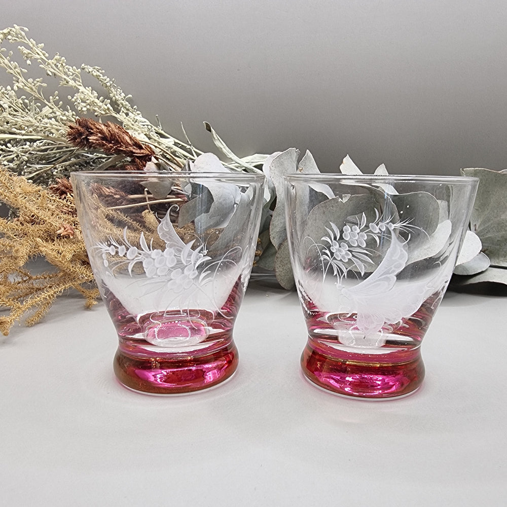 Pair of etched cranberry glass liqueur glasses with floral engravings and pink bases.