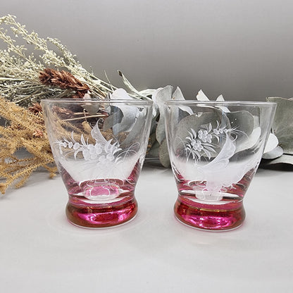 Pair of etched cranberry glass liqueur glasses with floral engravings and pink bases.