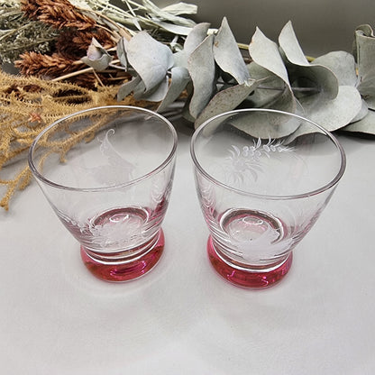 Pair of etched cranberry glass liqueur glasses with floral engravings and pink bases.