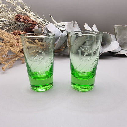 Pair of etched green glass shot glasses with clear tops and vibrant green bases.