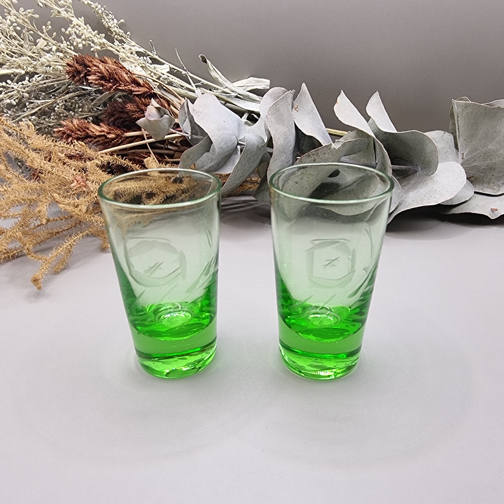 Pair of etched green glass shot glasses with clear tops and vibrant green bases.