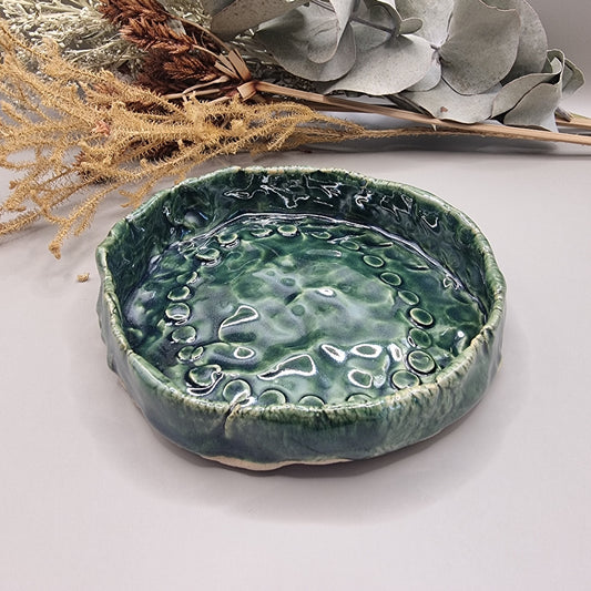 Handmade green ceramic dish with rippled glossy surface and organic edges