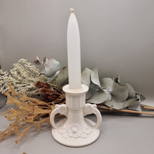 White ceramic twin handle candle holder with raised floral base detail and glossy glaze.