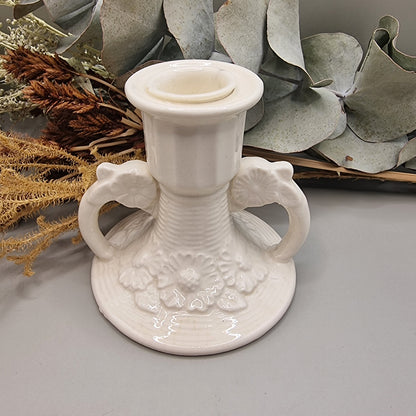 White ceramic twin handle candle holder with raised floral base detail and glossy glaze.