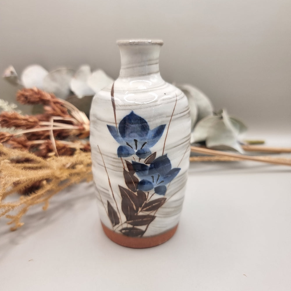 Vintage hand-painted ceramic bud vase with blue floral design and terracotta base.