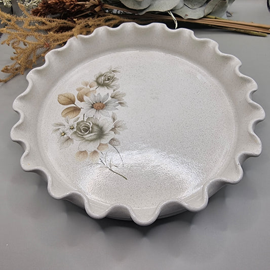 Vintage flan dish with floral pattern and wavy scalloped edge.