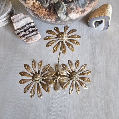 Vintage brass earring holder with three daisy flowers and petal holes for displaying earrings.