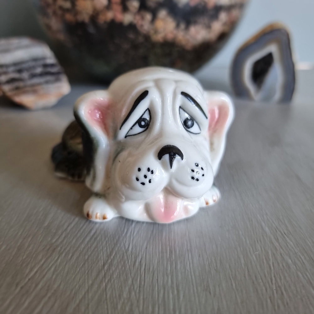Vintage ceramic dog figurine with droopy eyes and pink ears.