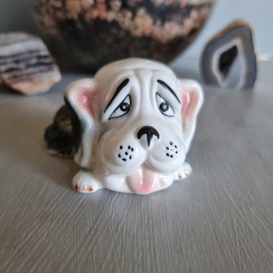 Vintage ceramic dog figurine with droopy eyes and pink ears.