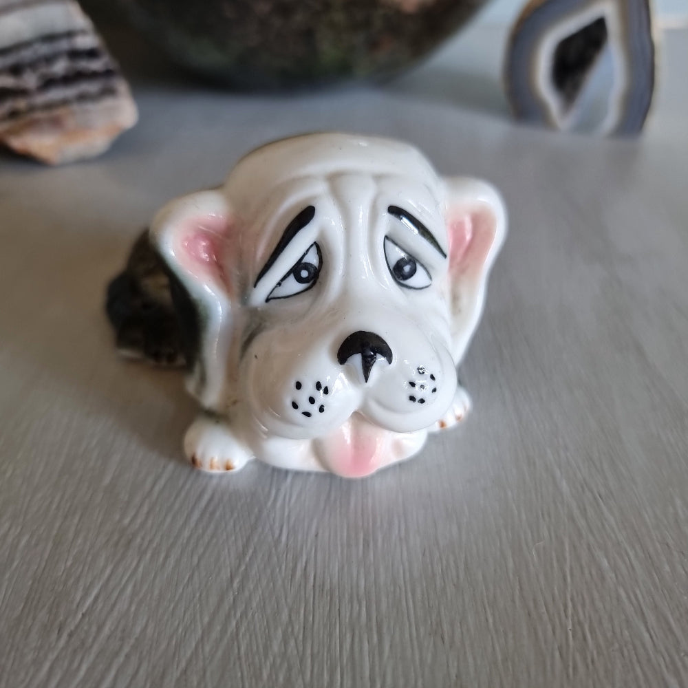 Vintage ceramic dog figurine with droopy eyes and pink ears.