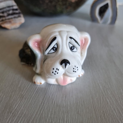 Vintage ceramic dog figurine with droopy eyes and pink ears.