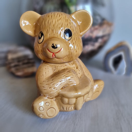 Vintage ceramic bear-shaped honey pot with cartoon eyes and paw prints.