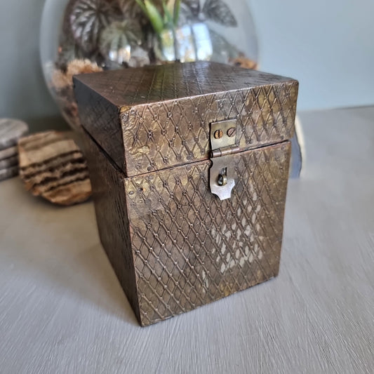 Square wooden box with diamond brass embossing and hinged lid.