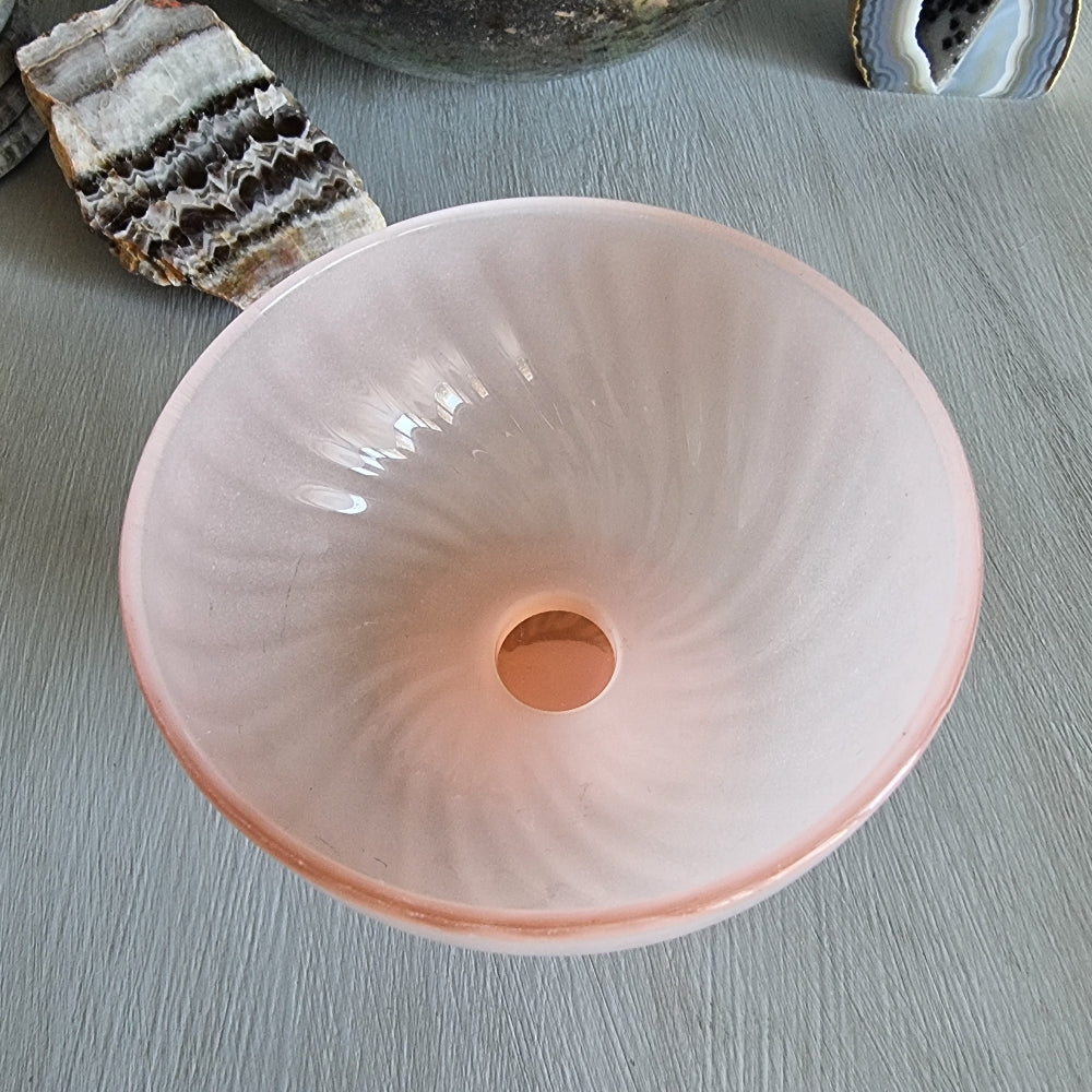 Vintage pink frosted glass bonbon dish with pedestal base and soft swirl pattern.