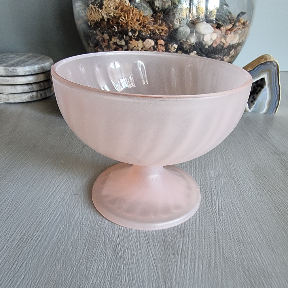 Vintage pink frosted glass bonbon dish with pedestal base and soft swirl pattern.