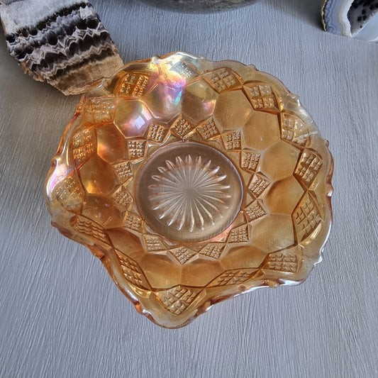 Amber carnival glass bowl with diamond pattern and scalloped edge, iridescent finish.