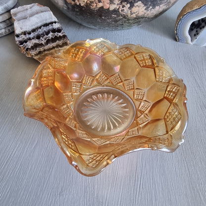 Amber carnival glass bowl with diamond pattern and scalloped edge, iridescent finish.