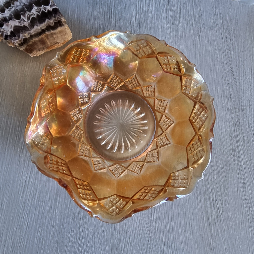 Amber carnival glass bowl with diamond pattern and scalloped edge, iridescent finish.