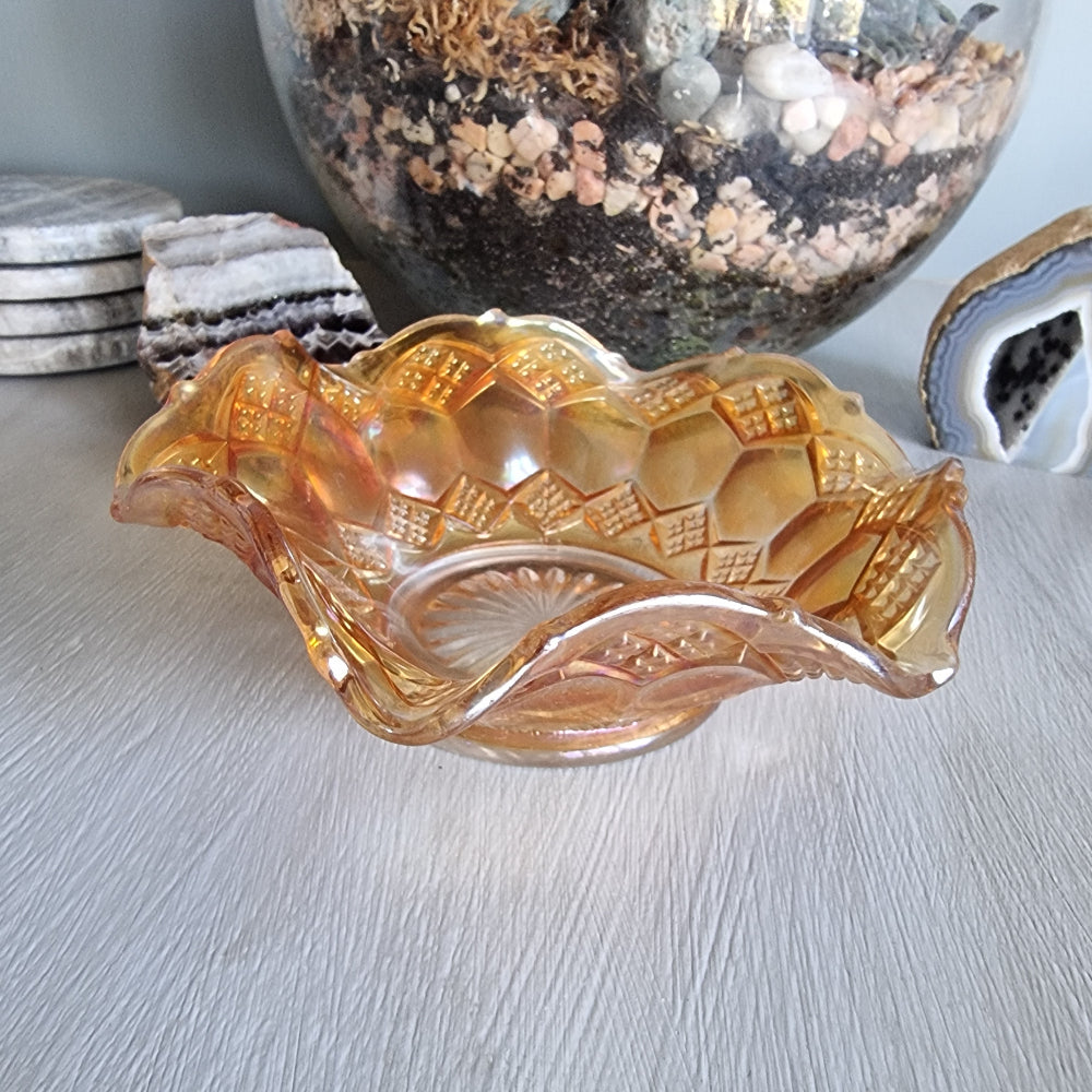 Amber carnival glass bowl with diamond pattern and scalloped edge, iridescent finish.