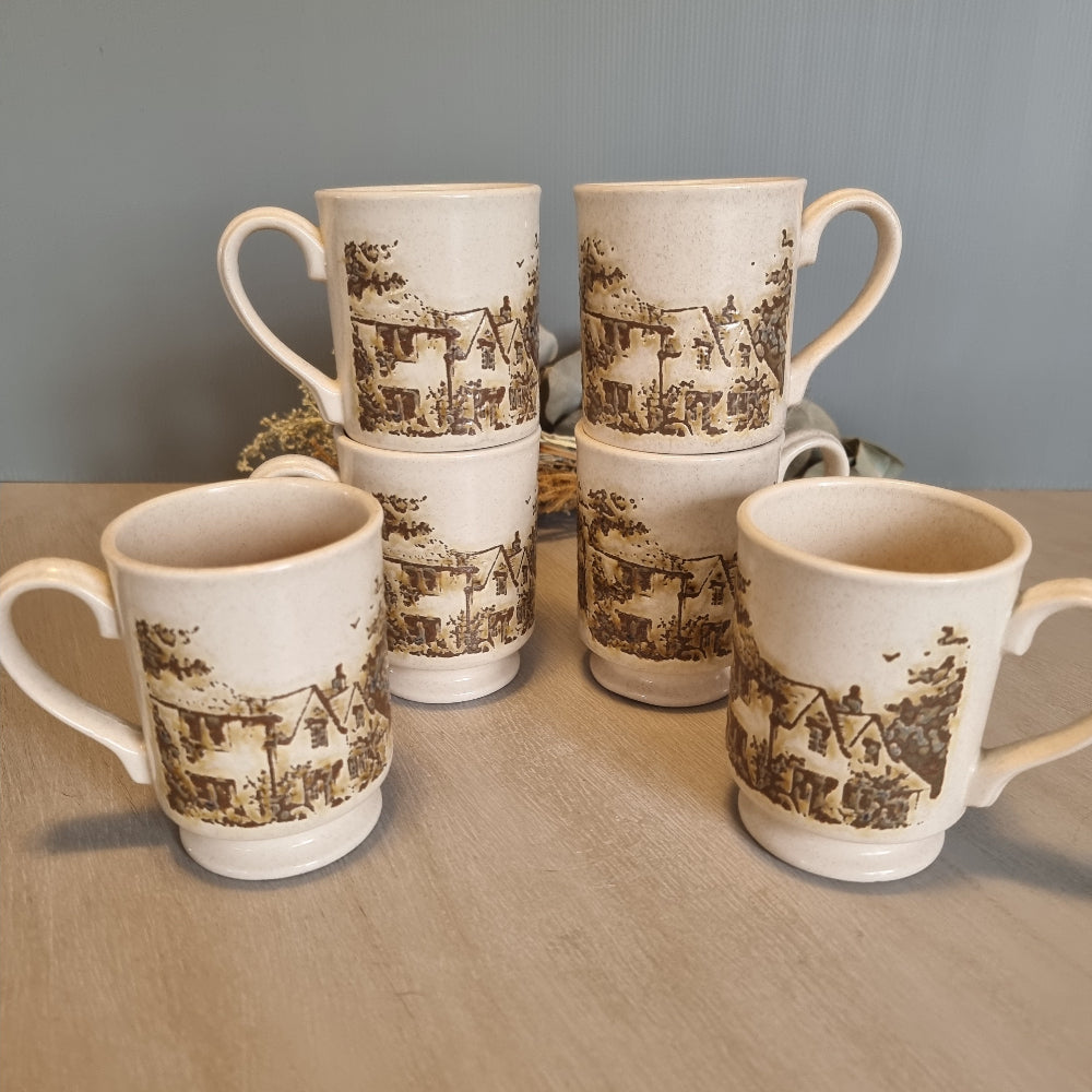 Set of six vintage stoneware mugs with brown cottage scene design on cream glaze.
