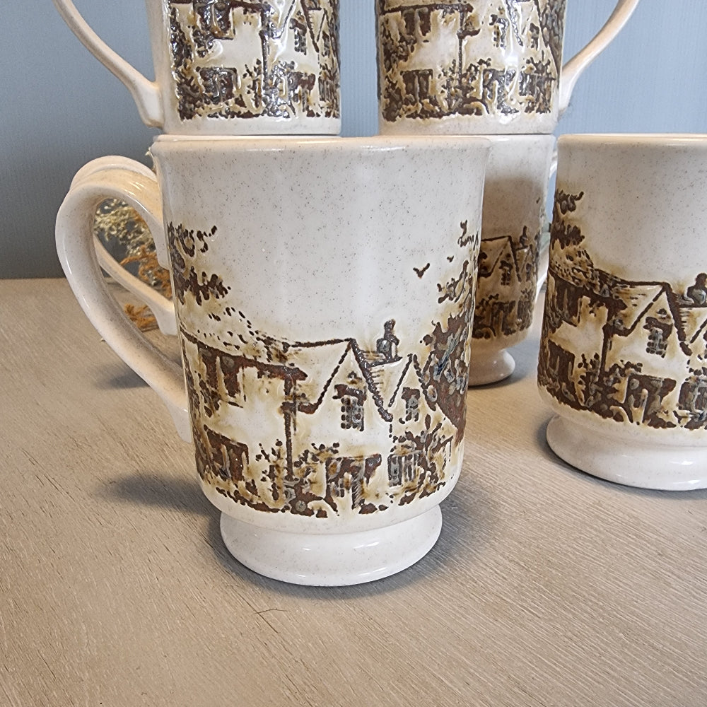 Set of six vintage stoneware mugs with brown cottage scene design on cream glaze.