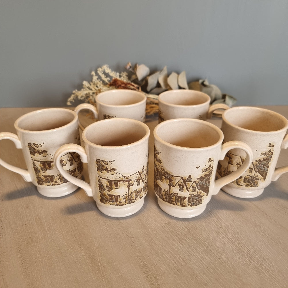 Set of six vintage stoneware mugs with brown cottage scene design on cream glaze.