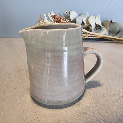 Handmade ceramic jug with blush and cream glaze, rustic and functional pottery piece.