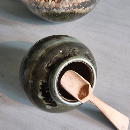 Vintage green glazed pottery salt jar with wooden scoop.