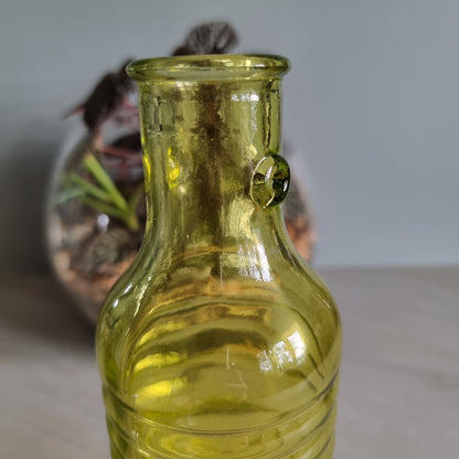 Vintage yellow-green ribbed glass bottle with small handles and retro charm.