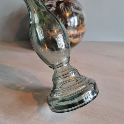Vintage green-grey glass candlestick holder with curving shape and translucent tone.