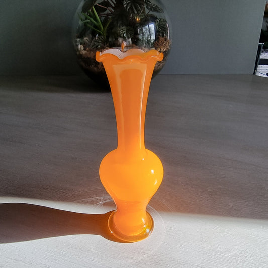 Vintage orange art glass vase with scalloped rim and bright retro tone.