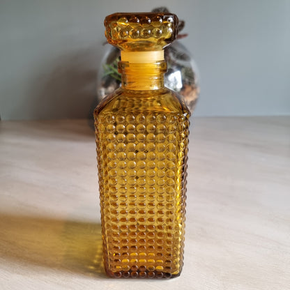 Vintage amber hobnail glass decanter with stopper and warm retro tone.