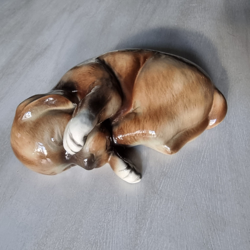 Vintage ceramic sleeping dog figurine in brown and cream glaze.