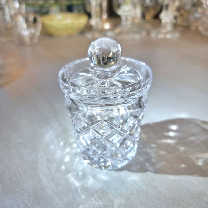 Small crystal jam jar with cut-glass lattice pattern and round lid knob catching the light.