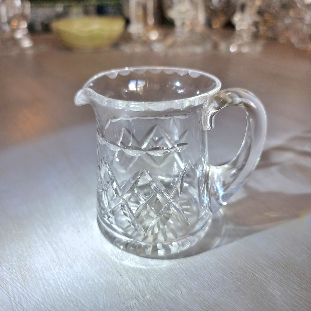 Pressed glass mini jug with scalloped rim and diamond-cut pattern.