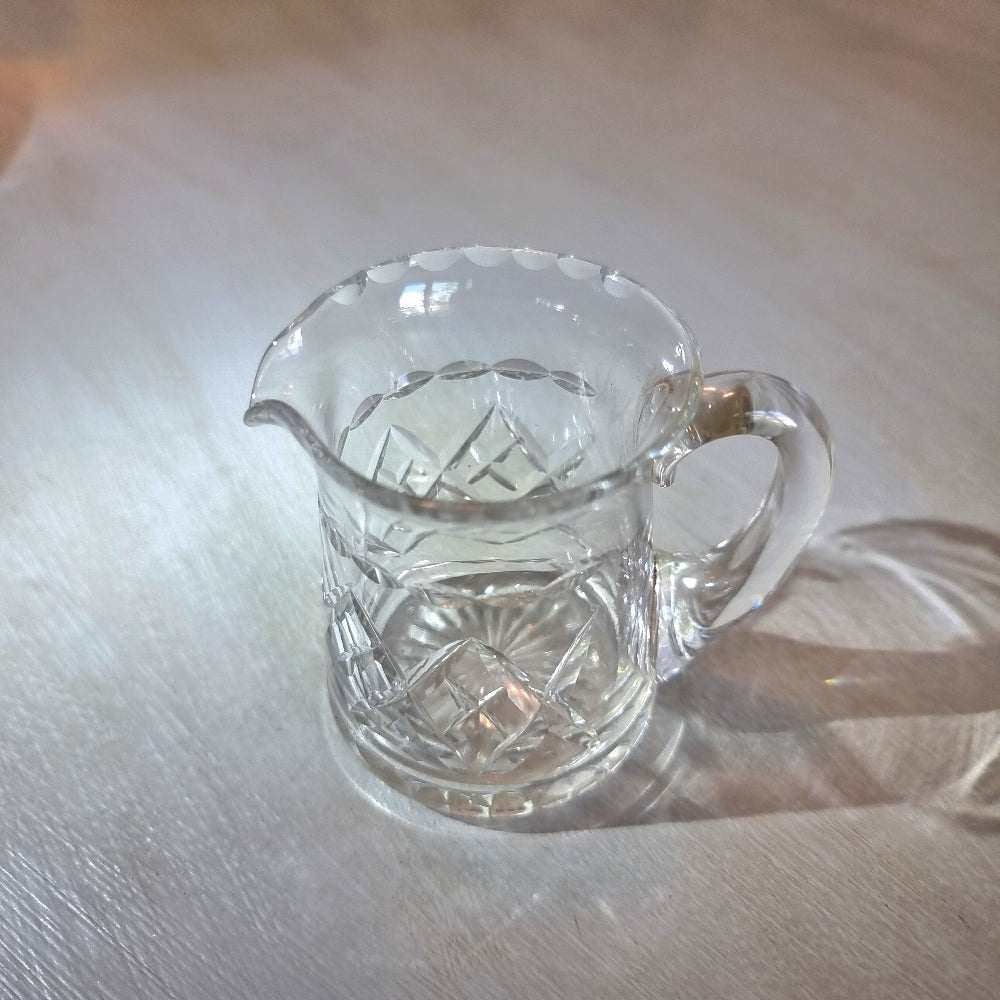 Pressed glass mini jug with scalloped rim and diamond-cut pattern.