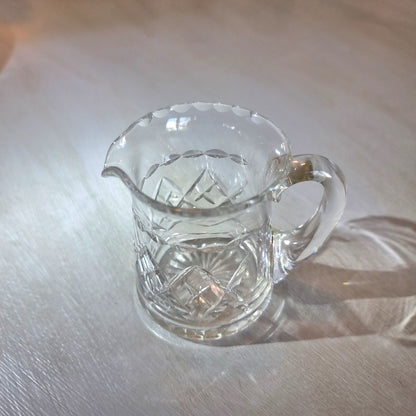 Pressed glass mini jug with scalloped rim and diamond-cut pattern.