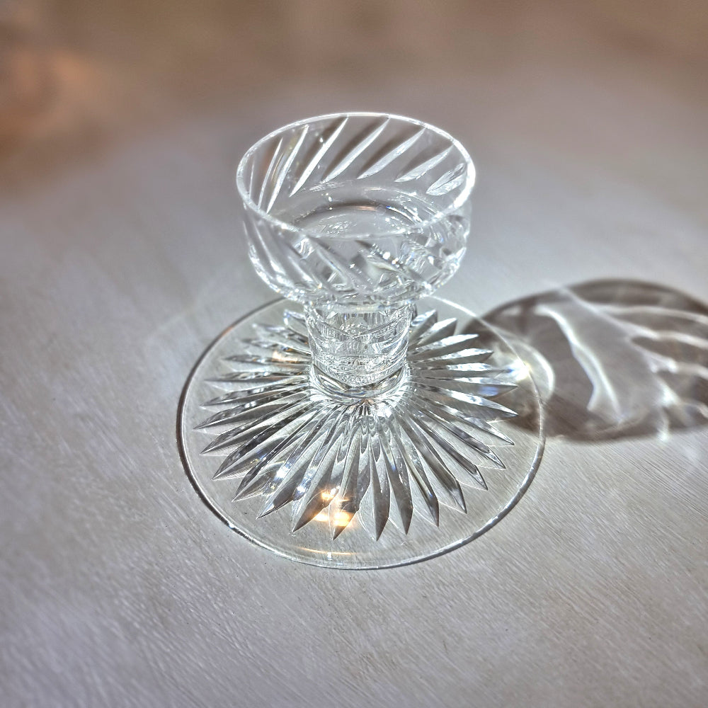 Crystal candle holder with cut starburst base and faceted swirl-pattern cup.