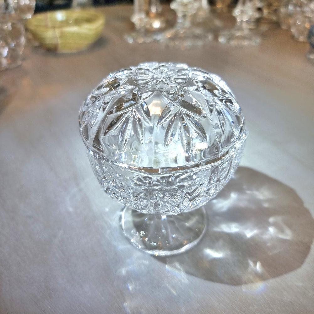 Crystal lidded pedestal bowl with faceted cut-glass pattern and domed lid.