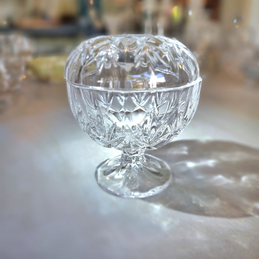 Crystal lidded pedestal bowl with faceted cut-glass pattern and domed lid.