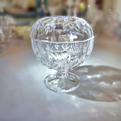Crystal lidded pedestal bowl with faceted cut-glass pattern and domed lid.