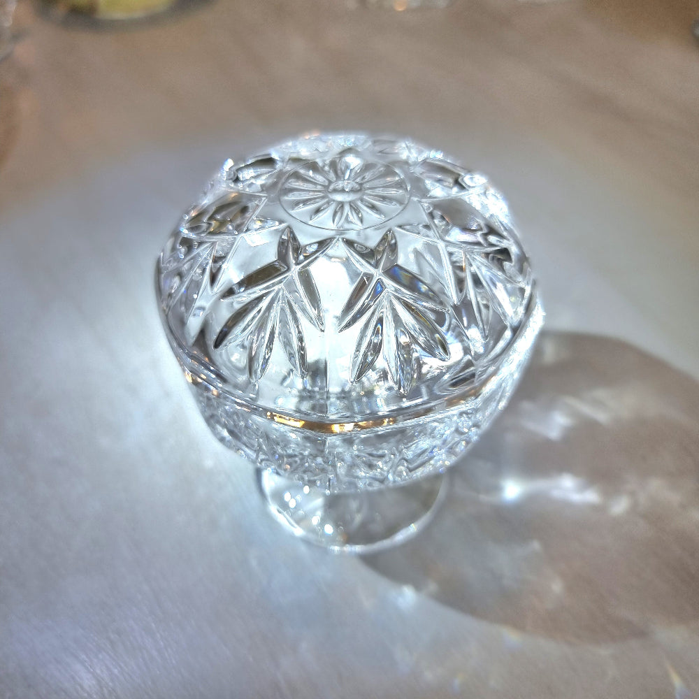 Crystal lidded pedestal bowl with faceted cut-glass pattern and domed lid.