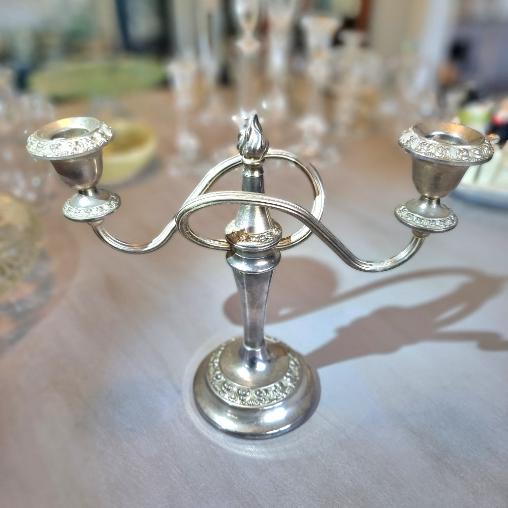 Silver two-arm candelabra with curved arms and ornate embossed detailing.