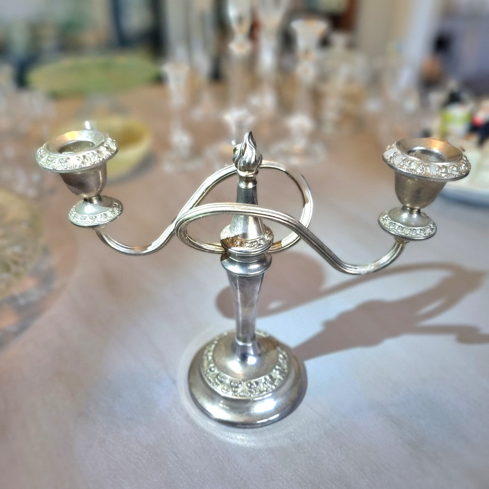 Silver two-arm candelabra with curved arms and ornate embossed detailing.