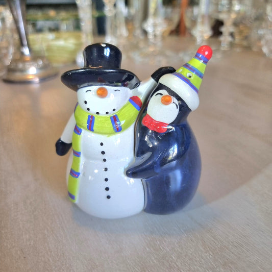 Ceramic salt and pepper shakers shaped as a hugging snowman and penguin.